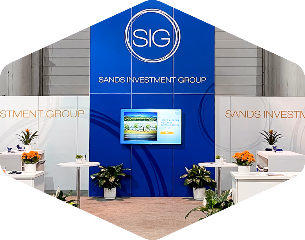 SIG trade show booth featuring branded signage, modern furniture, and digital display promoting commercial real estate services.