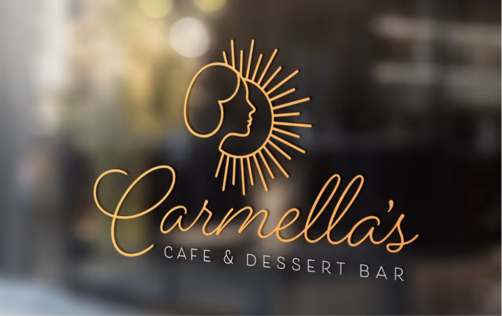 Window decal of Carmella’s Cafe & Dessert Bar logo featuring sunburst and feminine profile line art in gold.
