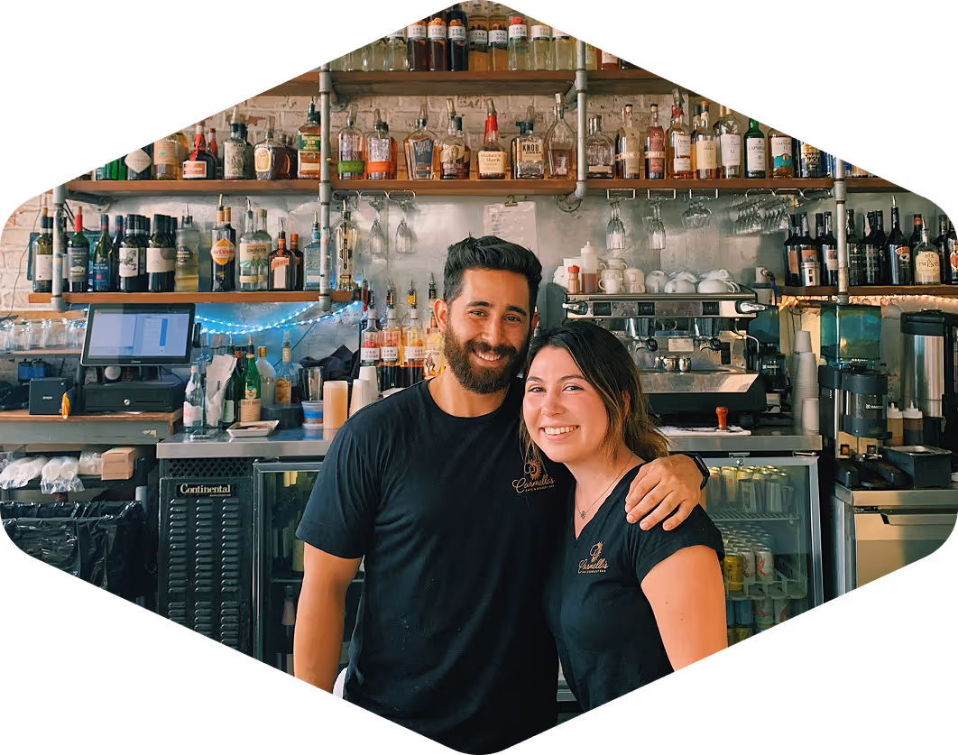 Smiling staff at Carmella’s Café & Dessert Bar standing behind a well-stocked bar, conveying a warm and welcoming customer experience.