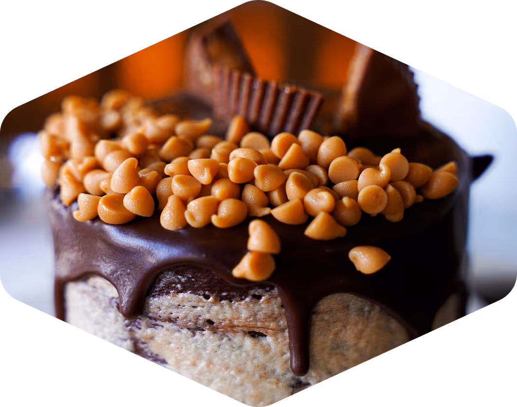 Decadent chocolate cake topped with peanut butter chips and Reese’s, perfect for highlighting rich dessert offerings.