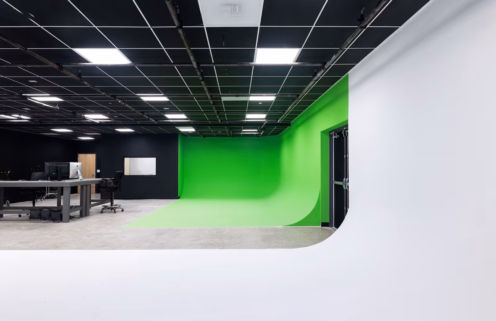 Corner view of Rift Studios showing green screen cyc wall, editing desk setup, and professional lighting for video production.