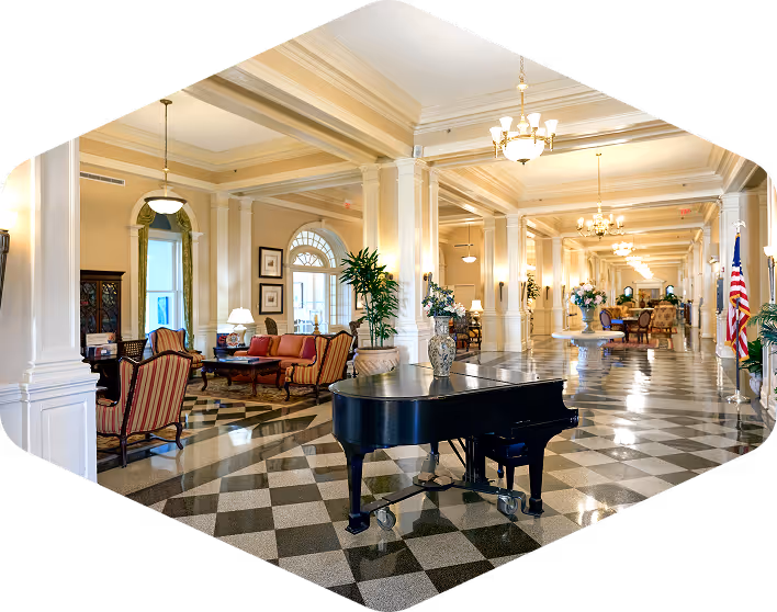 Luxurious lobby with black grand piano, chandeliers, and classical architecture at an upscale retirement or hospitality venue