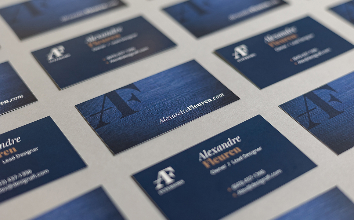 Angled overhead view of two-sided Alex Fleuren Interiors business cards.
