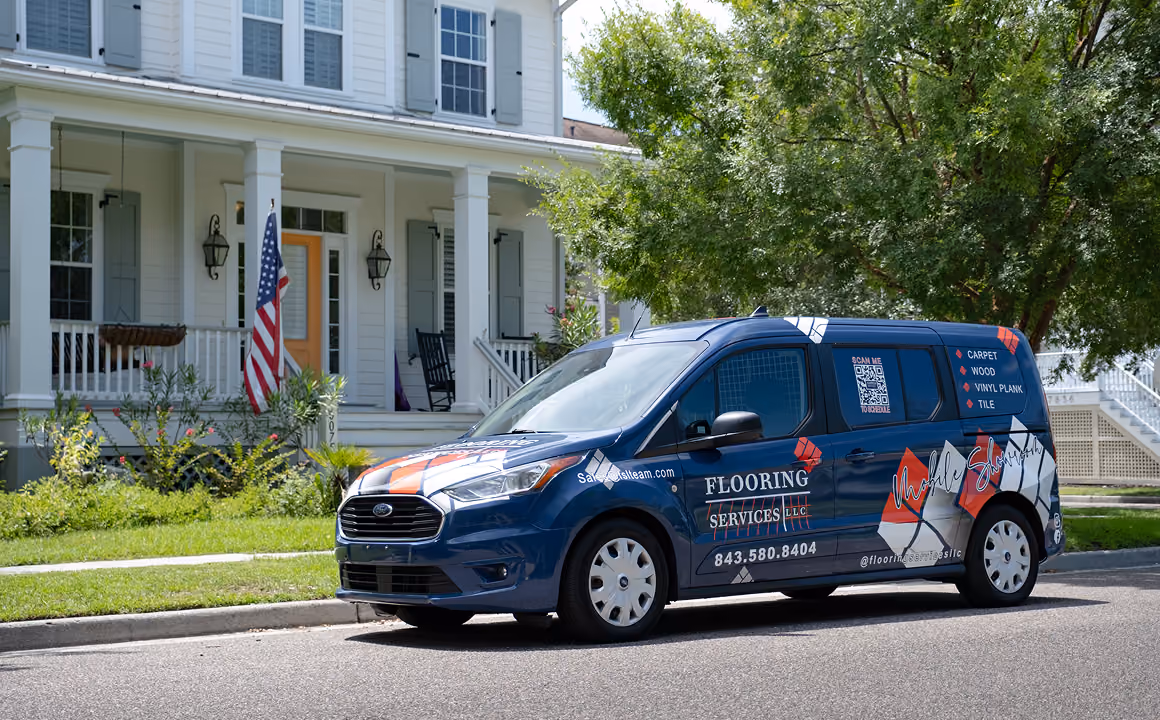 Blue Flooring Services LLC van parked in front of a large white residential home.