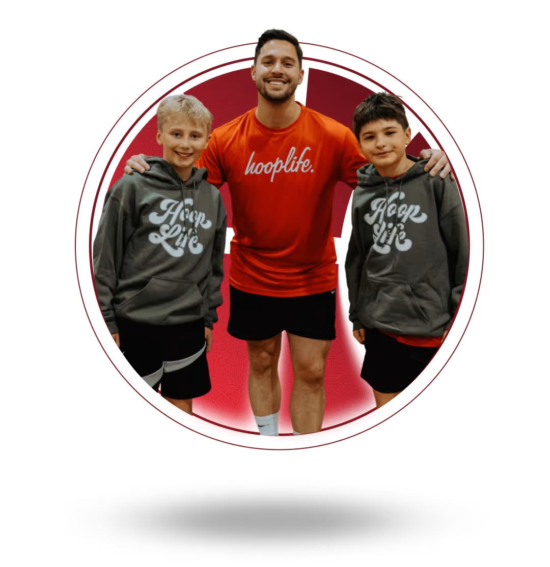 Smiling man in red hooplife shirt with arms around two boys wearing gray hoop life hoodies.