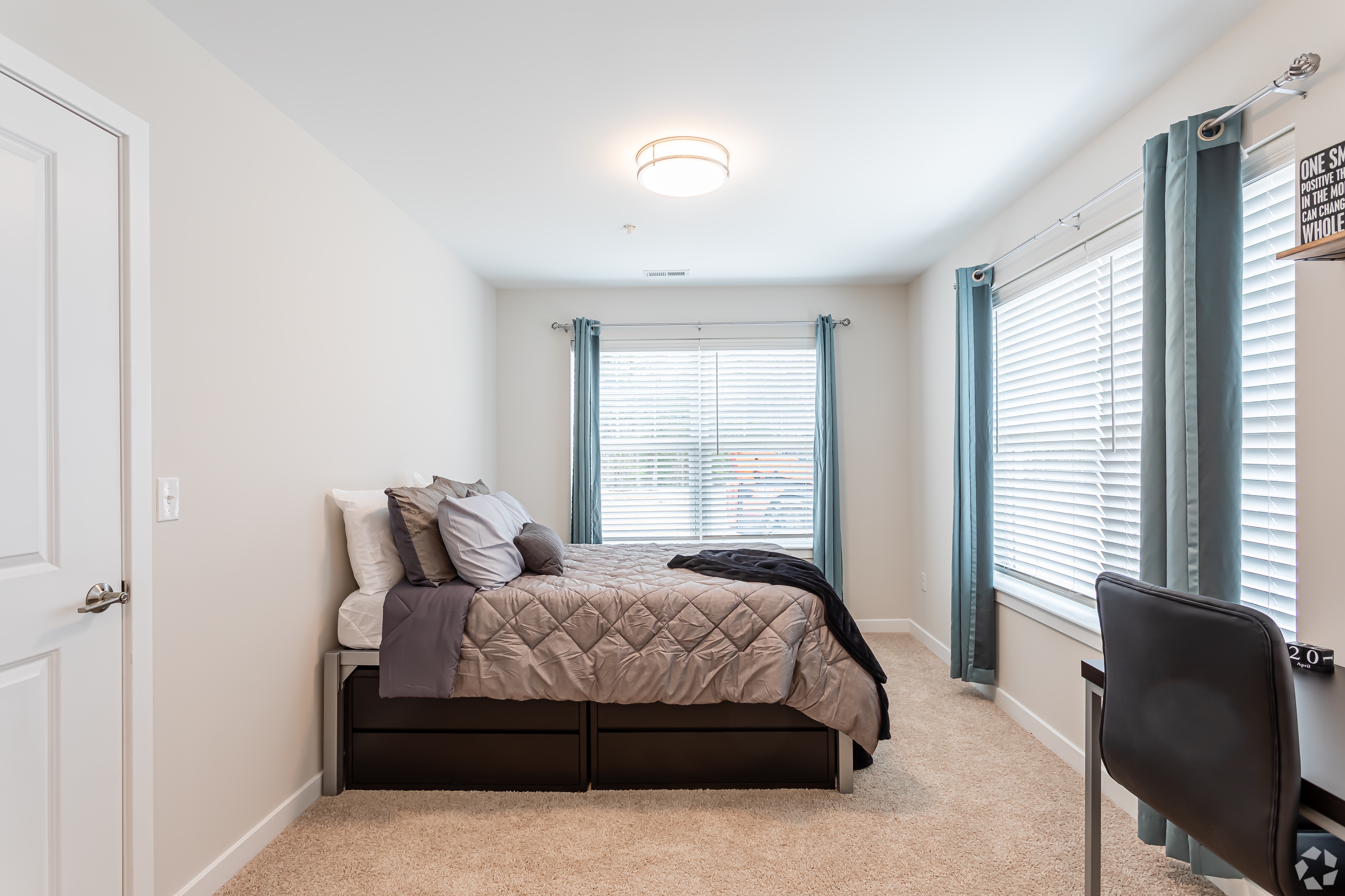 Furnished bedroom with bed and two corner windows