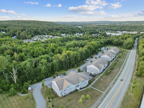 Residential street scene showing modern townhome apartment buildings with individual garages and parked cars, at Meadowbrook Gardens in Mansfield Center, CT.