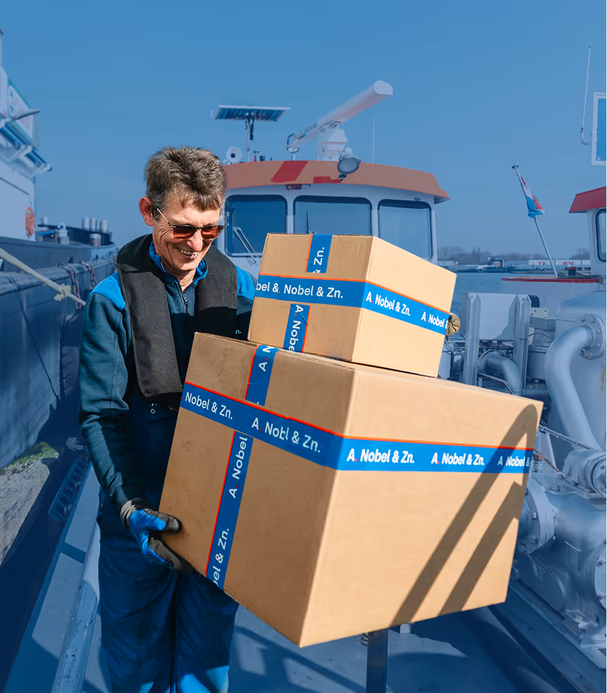 Bunkerschipper van Nobel loopt met twee dozen over het dek van de Nobel bunkerboot