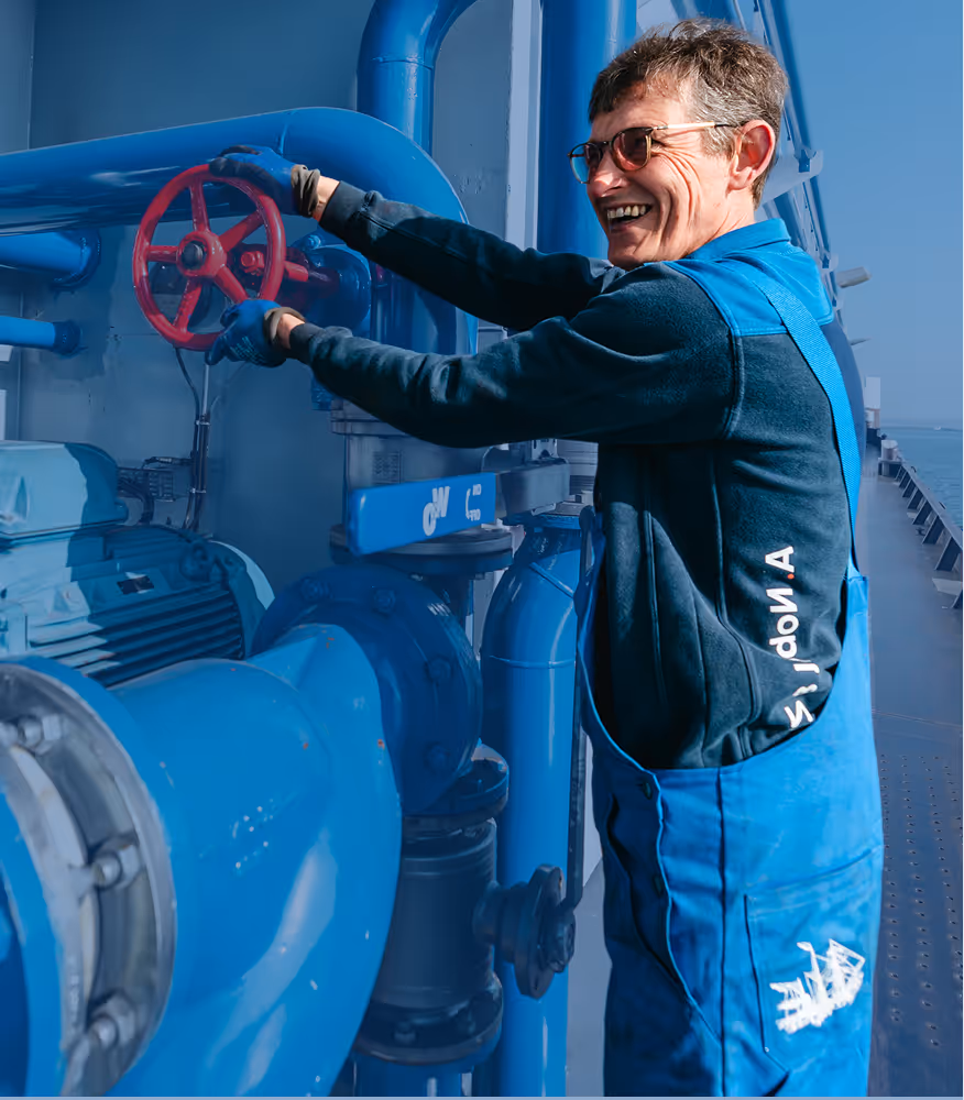 Bunkerschipper draait aan wiel en lacht op het bunkerstation de Tubantia van Nobel