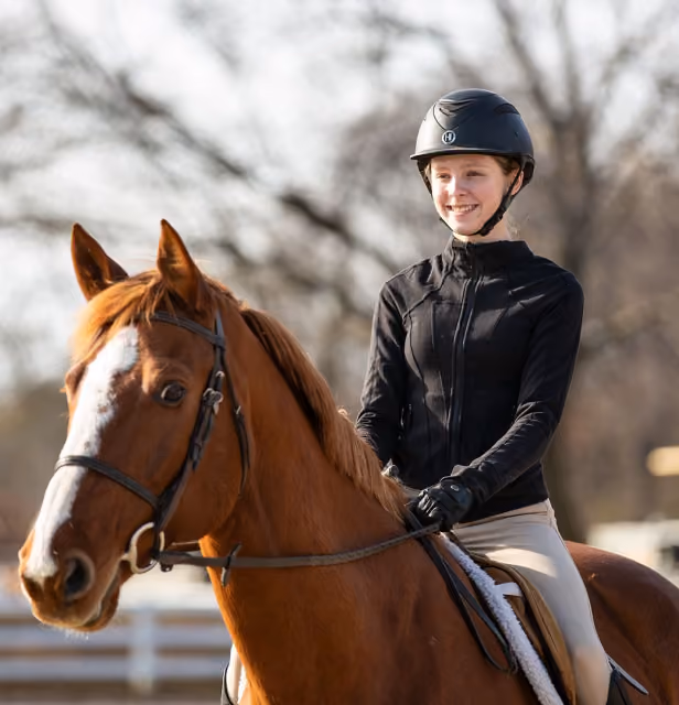 child smiling while riding a horse