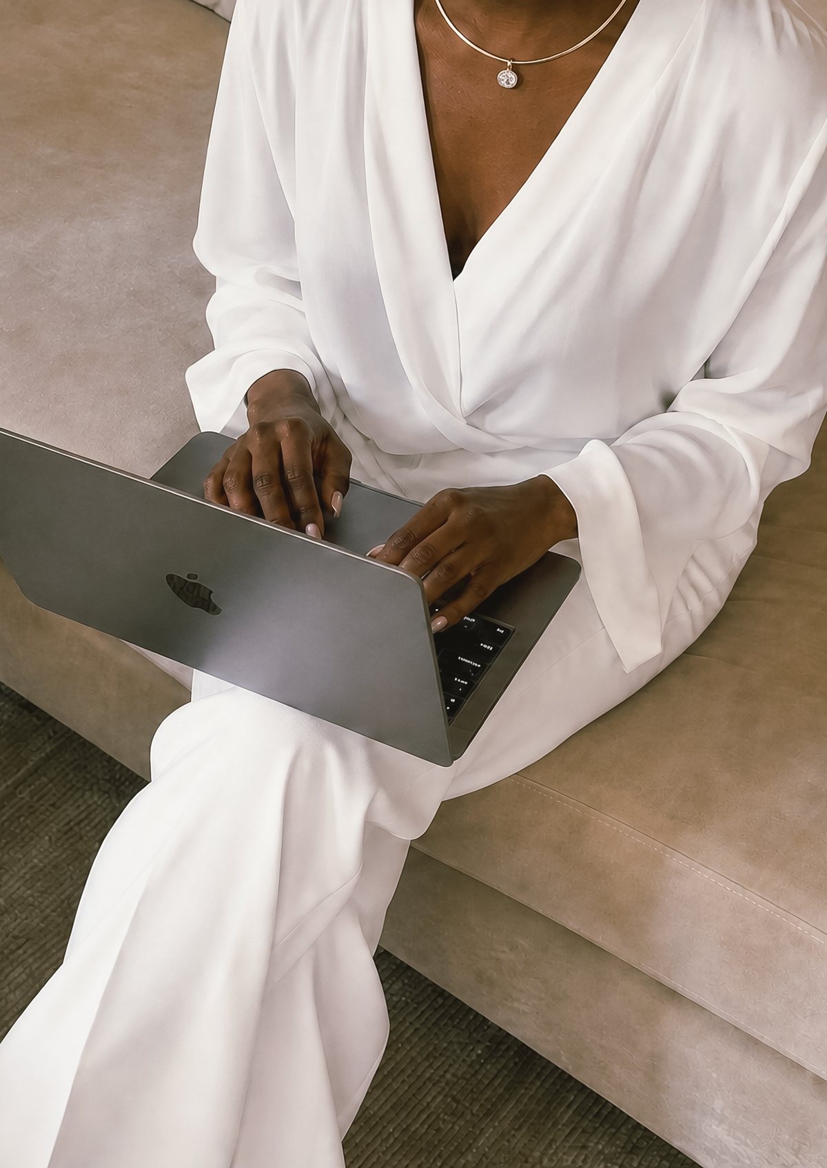 Professional woman in a white suit working on a laptop