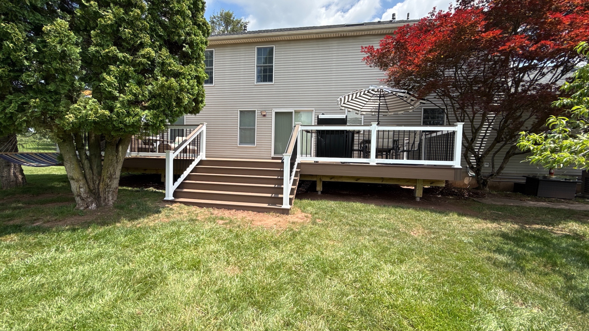 Front view of new composite deck in Milford NJ with white railings and brown decking