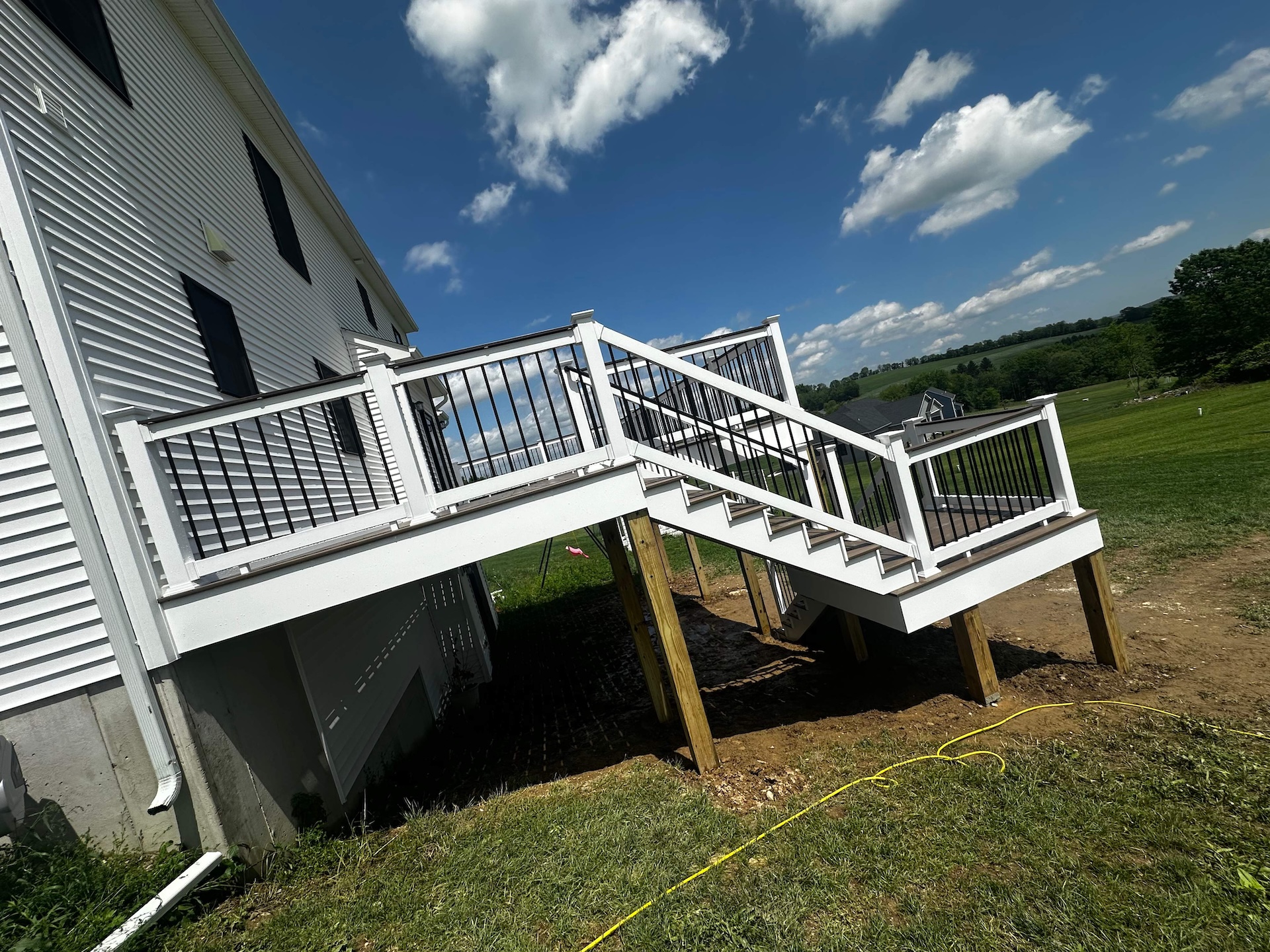 Elevated deck stairs with white railings and black balusters