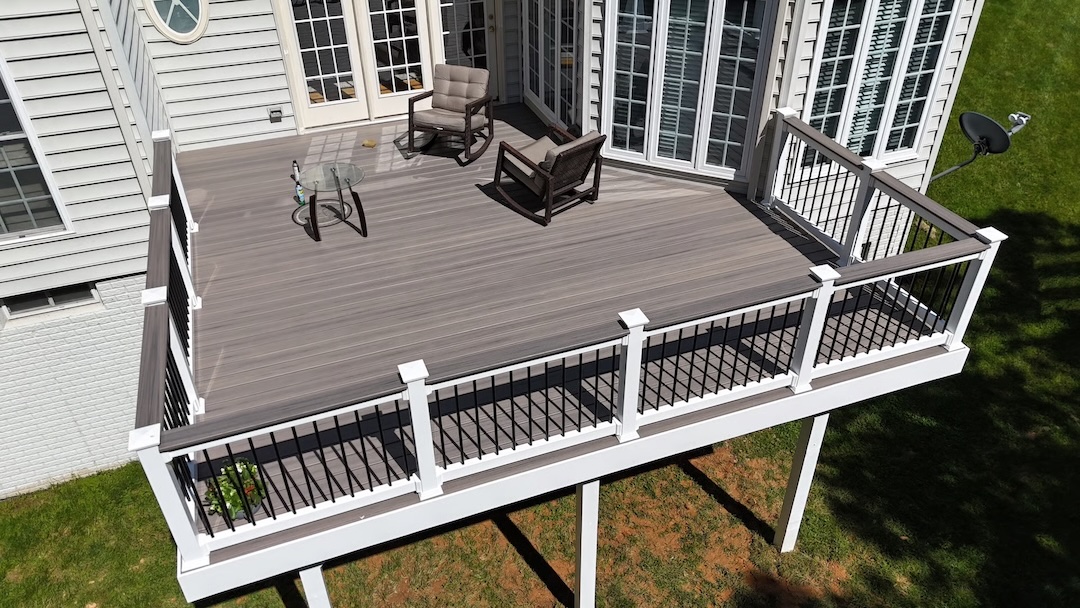 Spacious composite deck with white and black railings, featuring cozy outdoor seating, designed by Upgryd for modern style and low-maintenance durability