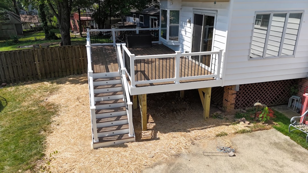 PVC deck with white railings and black balusters, featuring a stairway to the yard, designed by Upgryd for low-maintenance performance and seamless backyard access