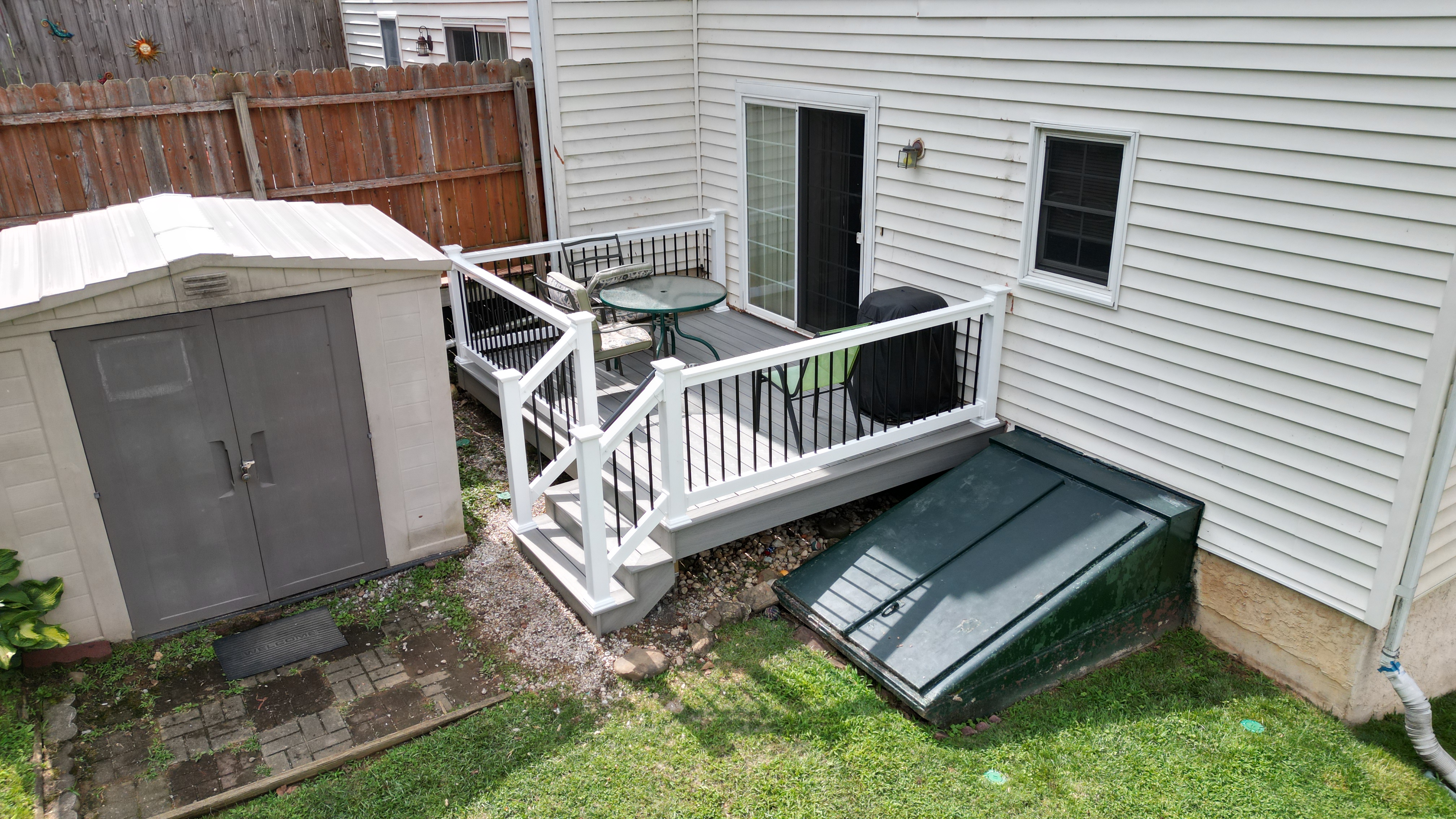 Angled aerial view of a resurfaced deck in Easton, PA with gray composite decking, white vinyl railing, black aluminum balusters, and stair access from the backyard.