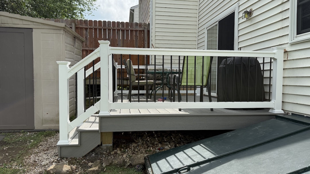 Small resurfaced deck with gray composite decking and white vinyl railing with black balusters.