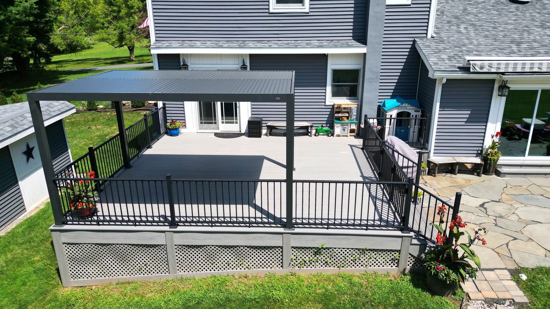 Resurfaced deck with Deckorators Summit Glacier decking, black aluminum railing, and a louvered pergola in Hampton, NJ.