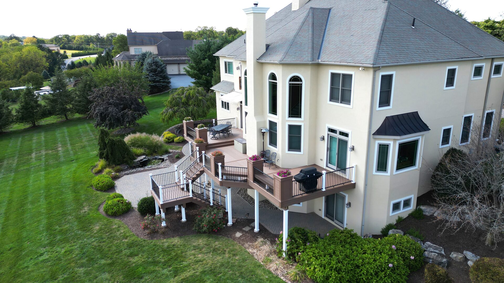 Multi-tier deck with Deckorators Summit Boulder decking and black aluminum railing at golden hour in Orefield, PA.