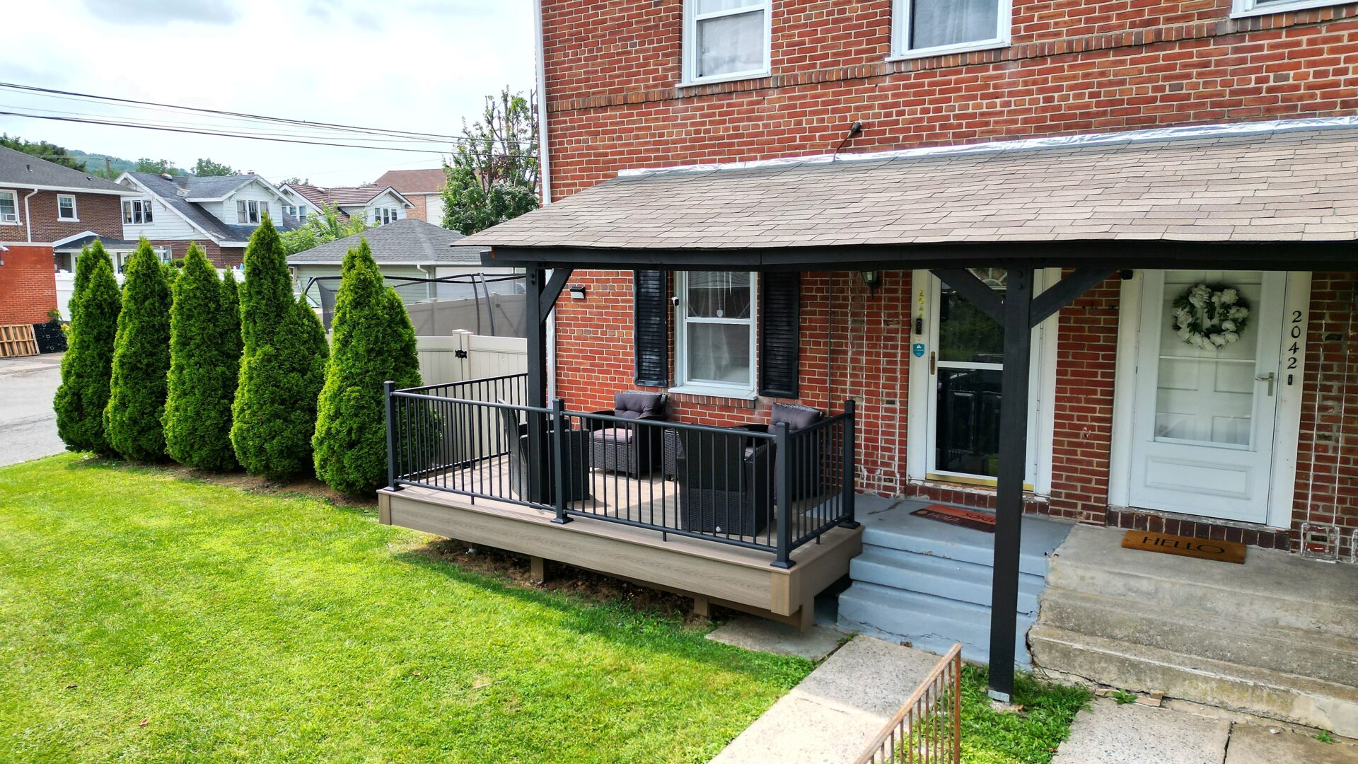 New front-entry deck with Deckorators Venture Sandbar decking and black aluminum railing in Allentown, PA.