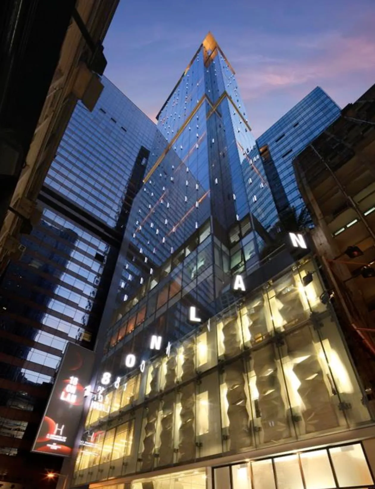 Ref#3006 is a modern glass skyscraper with illuminated ONLAN letters on its facade, offering warm-lit spaces ideal for renting as offices or restaurants.