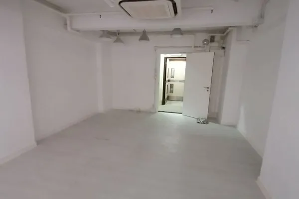 Ref#3149: An empty, white-walled space with exposed pipes and ductwork

ideal for shop or office rental. A white open door leads to another area, providing flexible business possibilities. No furnishings or decorations are included.