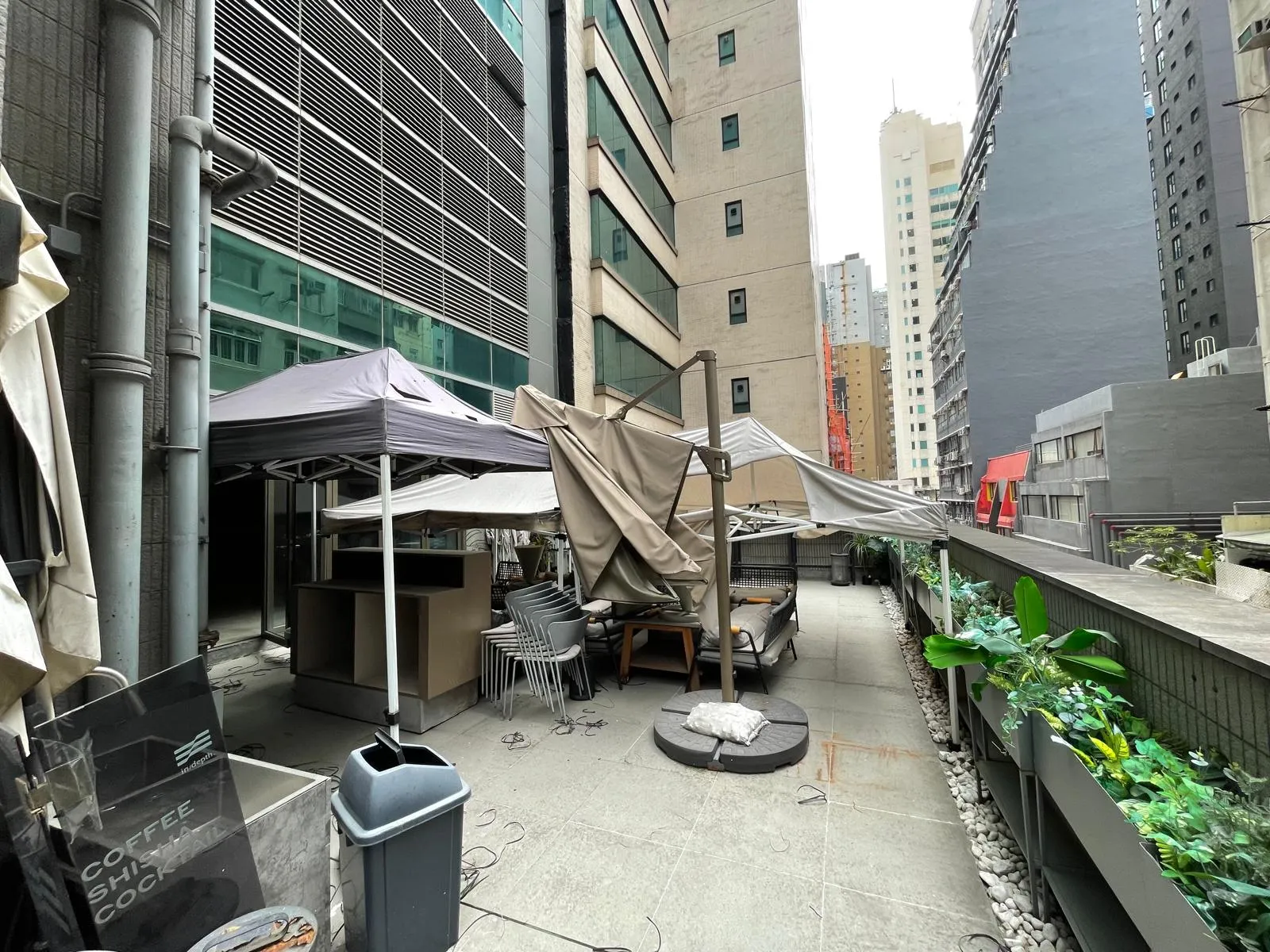 Outdoor patio on Wellington Street with overturned furniture, collapsed tents, and debris near tall Central city buildings.