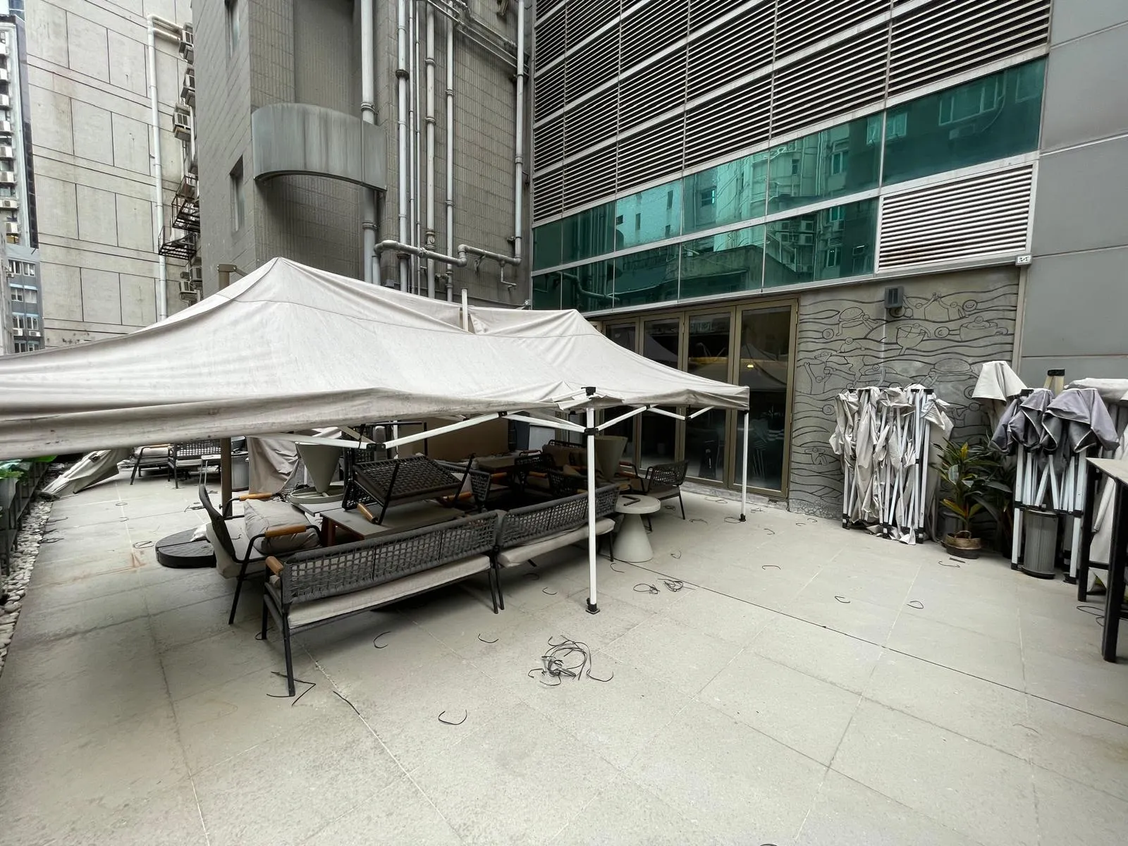 Outdoor patio with white canopy on Central benches tables and umbrellas next to a modern building on Wellington Street.