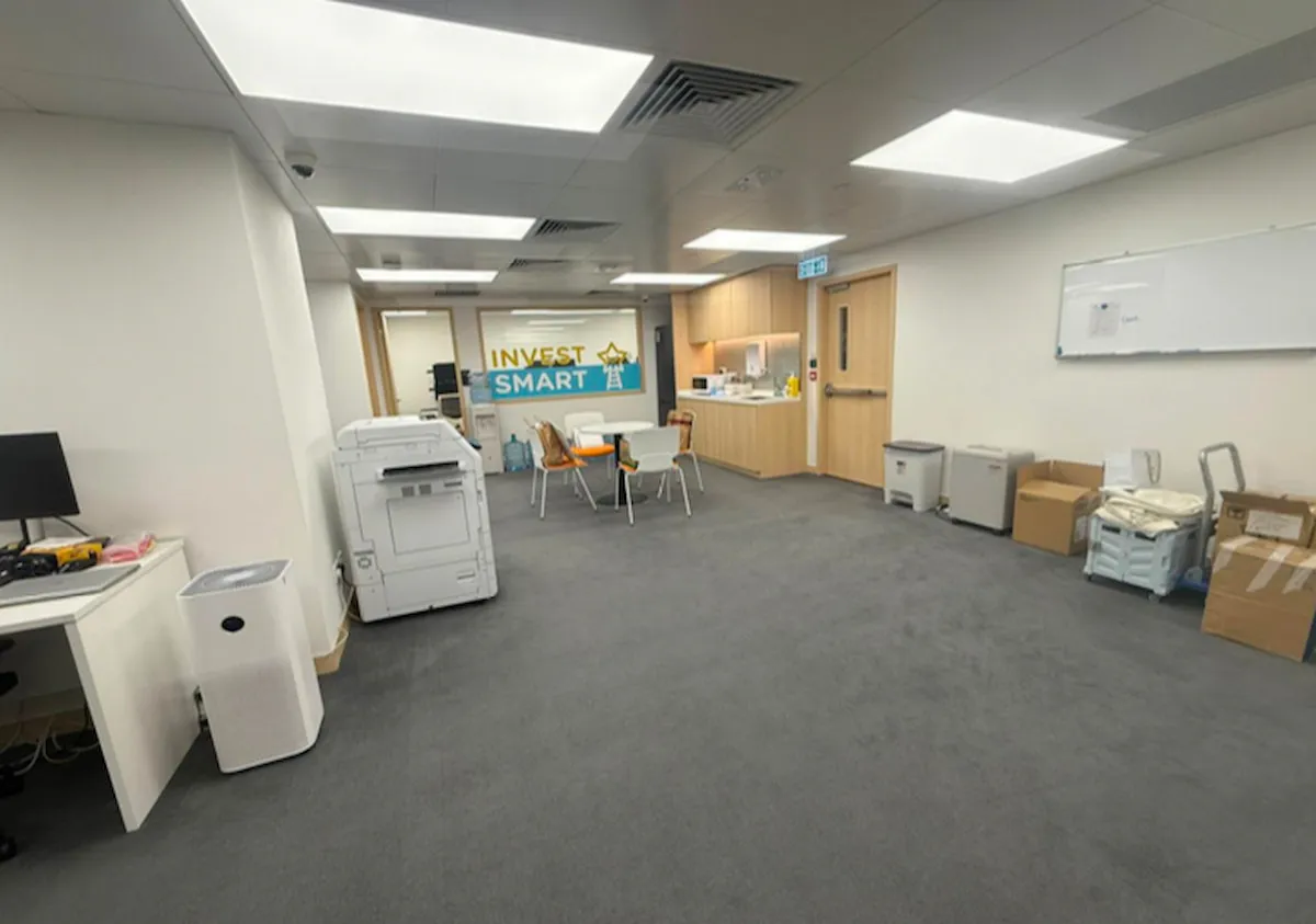 Office room on Shanghai Street Mong Kok with gray carpet desks chairs photocopier boxes and Invest Smart sign.