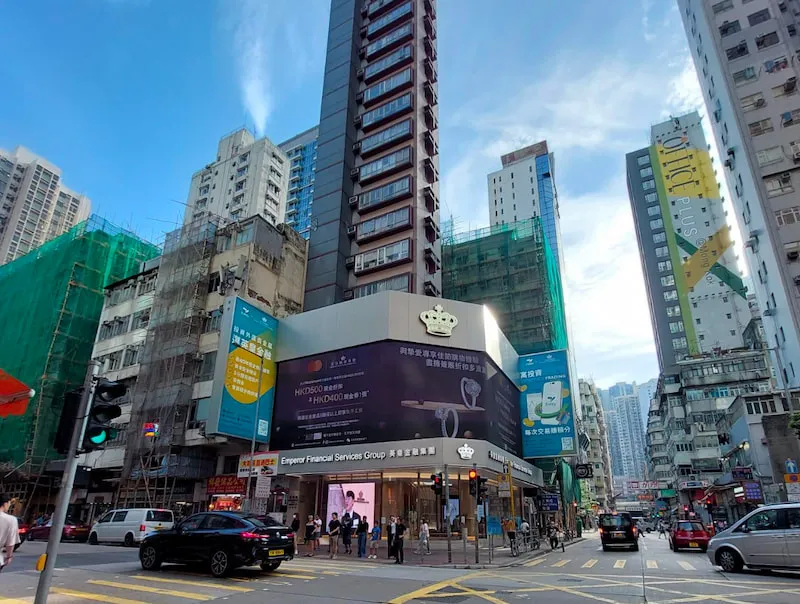 Crowds cross Shanghai Street at a Mong Kok intersection lined with tall buildings and neon billboards.