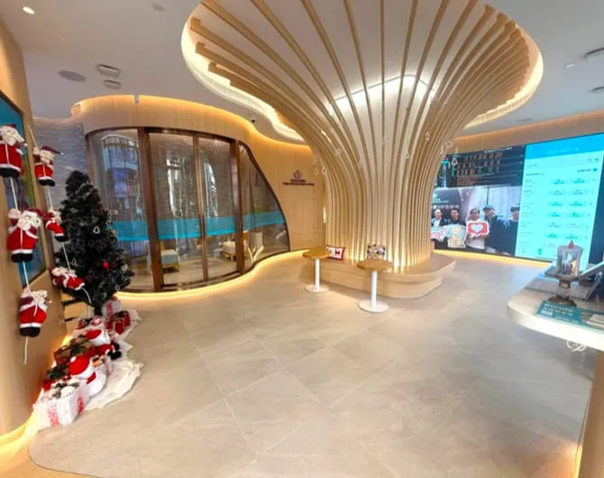 Modern lobby near Shanghai Street Mong Kok with large wooden column, Christmas decorations, black tree, and digital screens.