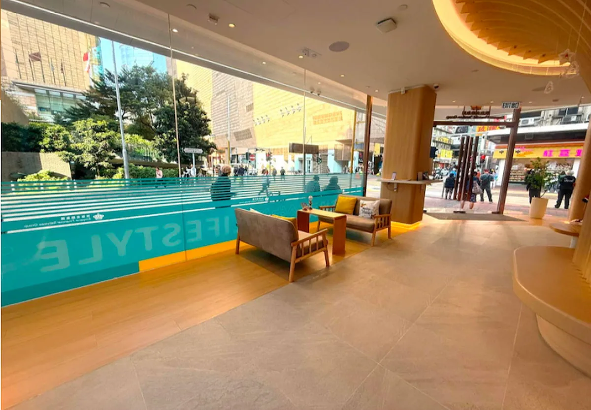 Lobby with chairs and tables by large glass windows, overlooking Shanghai Street in Mong Kok.