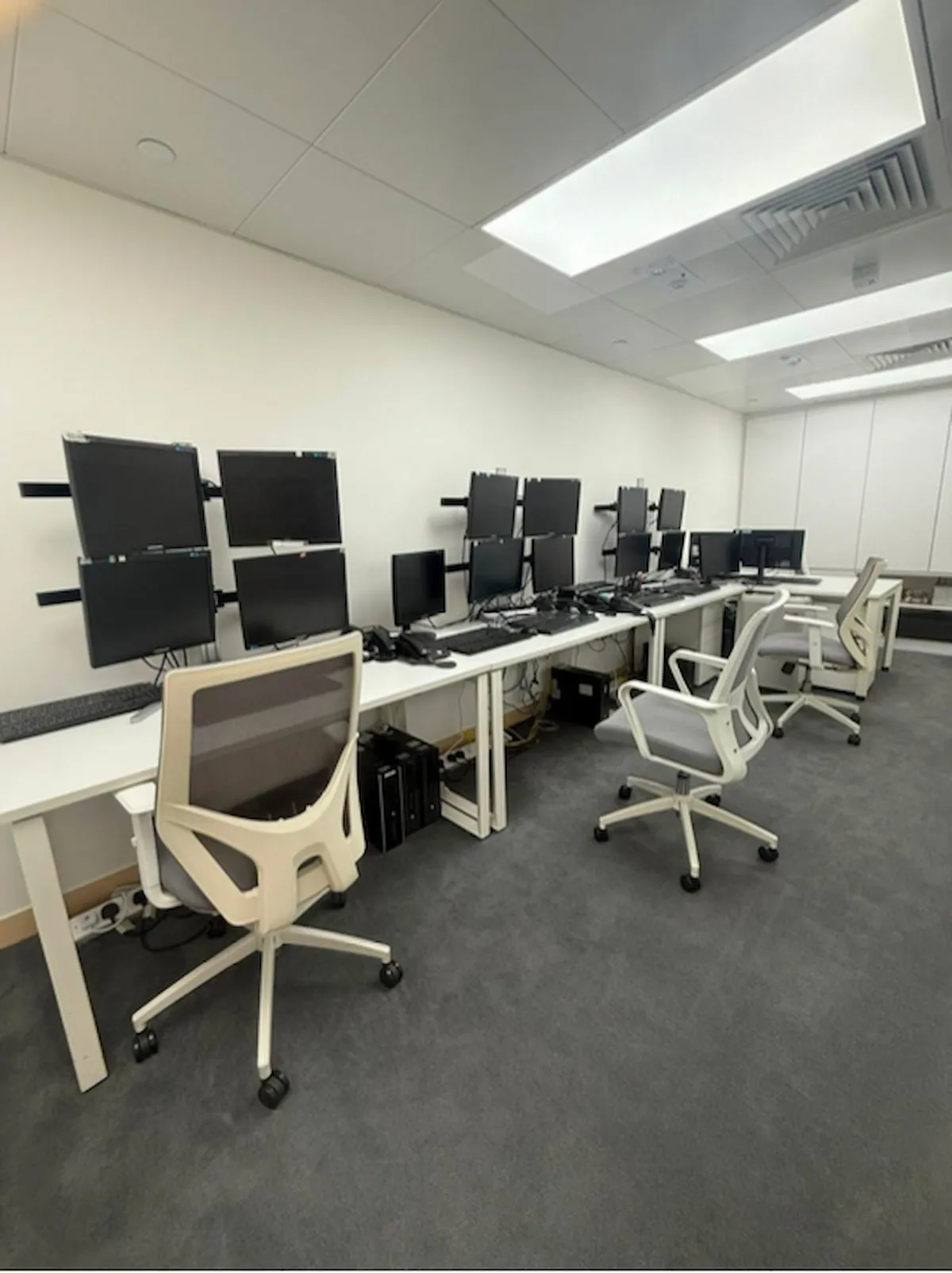 Modern office on Shanghai Street featuring empty chairs, multiple computer monitors, and a minimalist interior design.