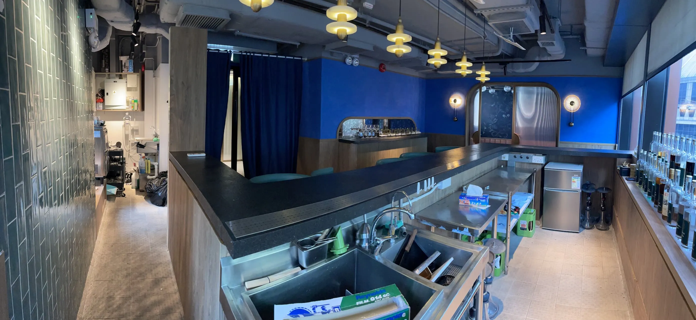 A bar on Wellington Street features a black counter, blue walls, and hanging lights in a modern interior.