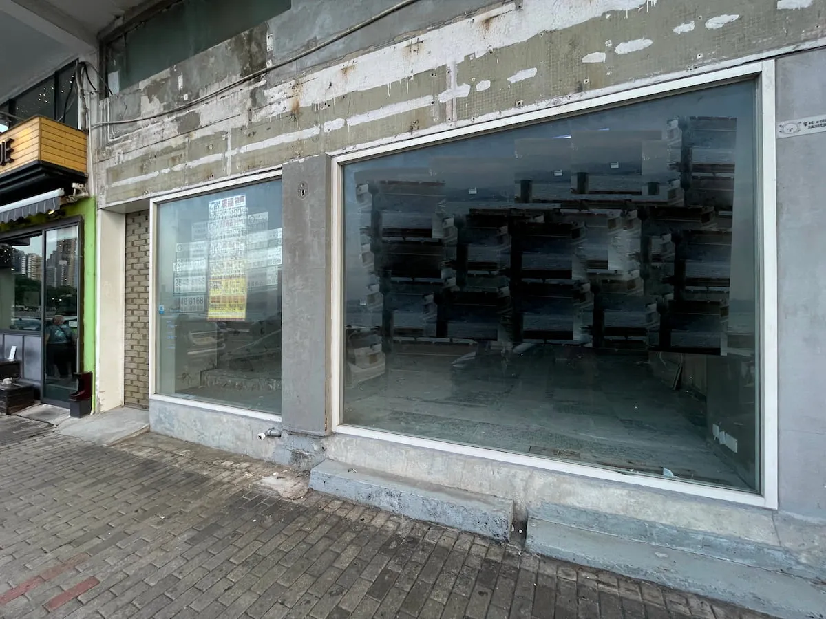 Ref#3608: Large, empty storefront with dusty windows and weathered exterior facing the sidewalk. Visible shelves and signs inside make it ideal for restaurant or shop rental.