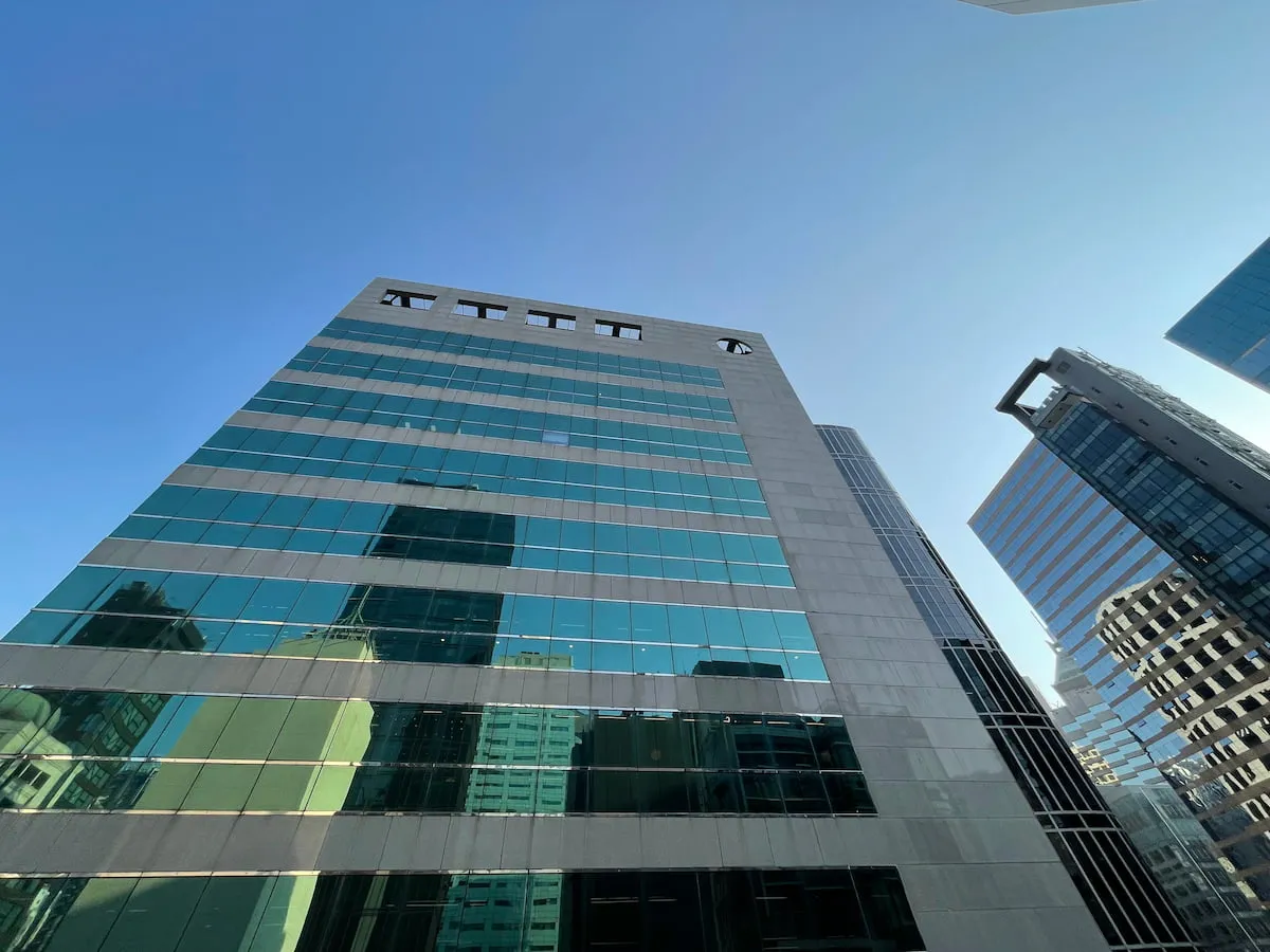 Tall glass office building on Central seen from below with nearby Wellington Street buildings and reflective windows.