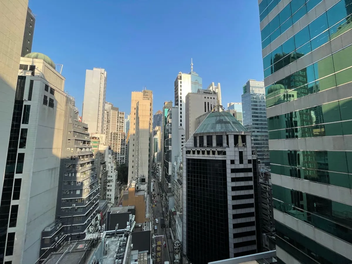 Tall modern buildings above Wellington Street in Central with a clear blue sky in the background.