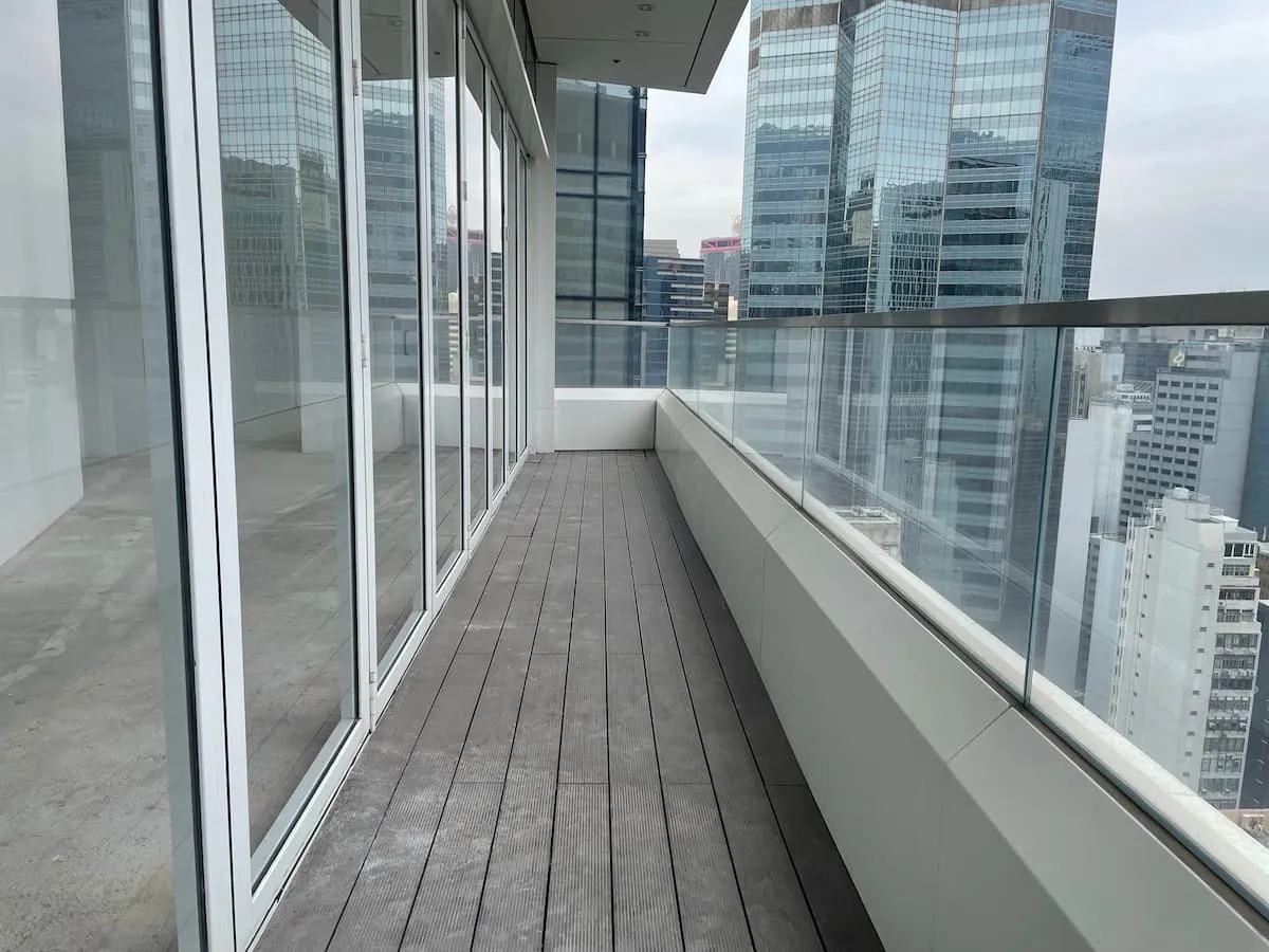 Ref#3616 features a modern balcony with glass railings and wooden flooring, overlooking city skyscrapers making it the perfect location to rent office or shop space in a vibrant urban setting.