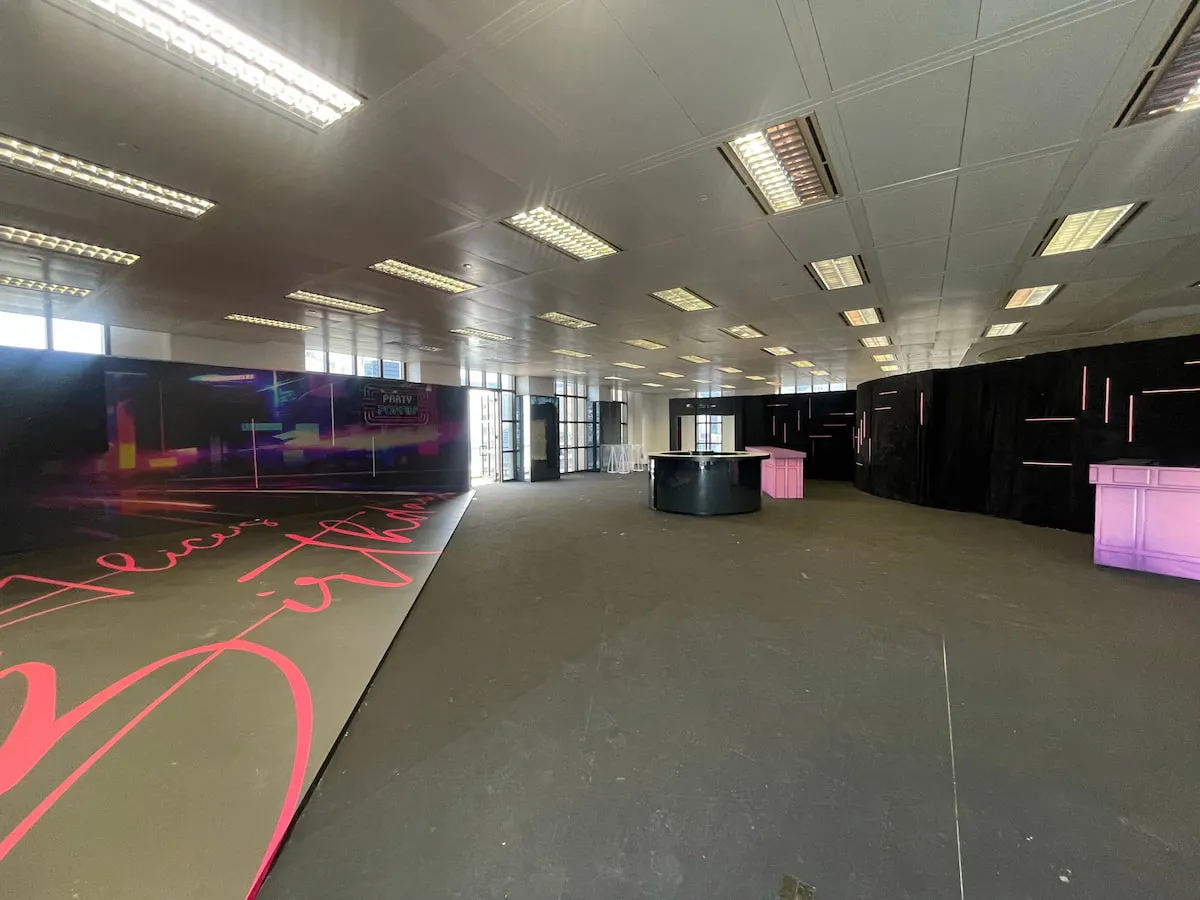 Ref#3609: A spacious, modern room with bright ceiling lights, dark flooring, and large windows—ideal for restaurant rentals. Features black and pink illuminated counters and a cheerful “Happy Birthday” cursive sign.