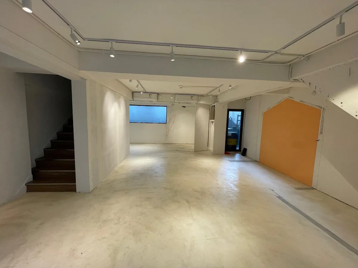 Ref#3622: Spacious, empty room with white walls, a yellow accent wall, window, and staircase. Bright ceiling lights and plain floor create an inviting spaceperfect to rent as an office or shop for your business vision.