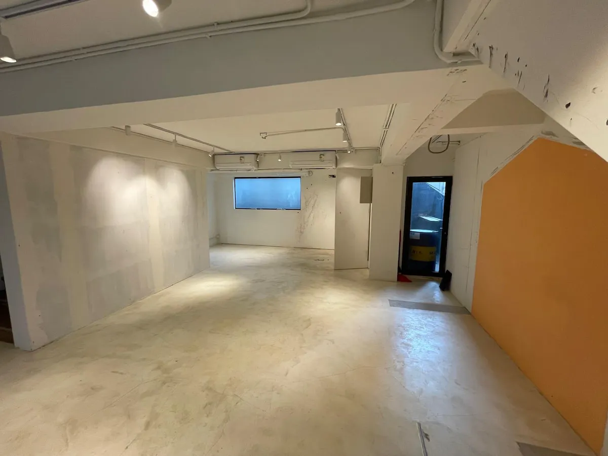 Ref#3622: Spacious empty room featuring white walls, a yellow accent wall, concrete floors, ceiling lights, and two windows
one beside a door to the outsideideal for office or shop rental.