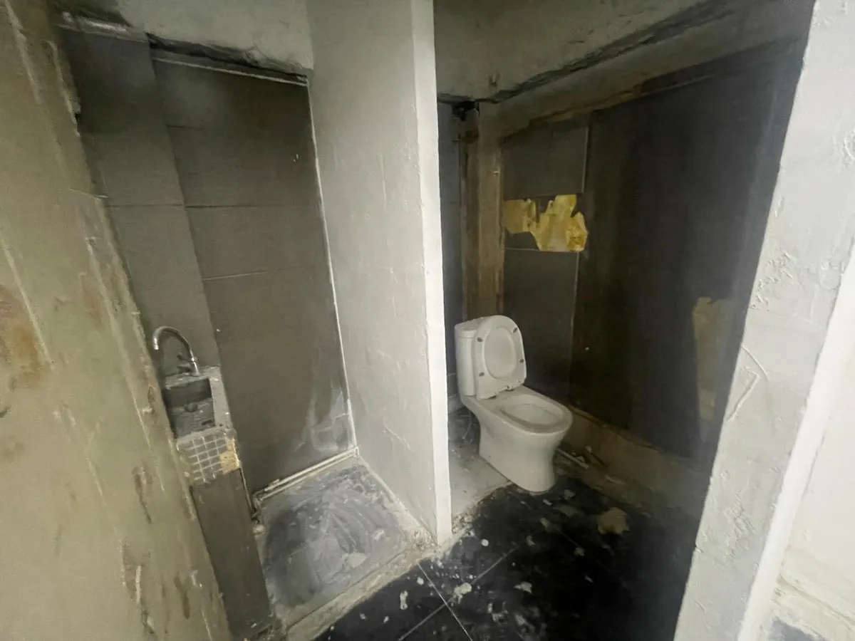 Ref#3623 features a dimly lit, run-down bathroom with a dirty toilet, small corner sink, stained floors, and peeling paint and tiles, highlighting the neglected condition of this rental shop space.