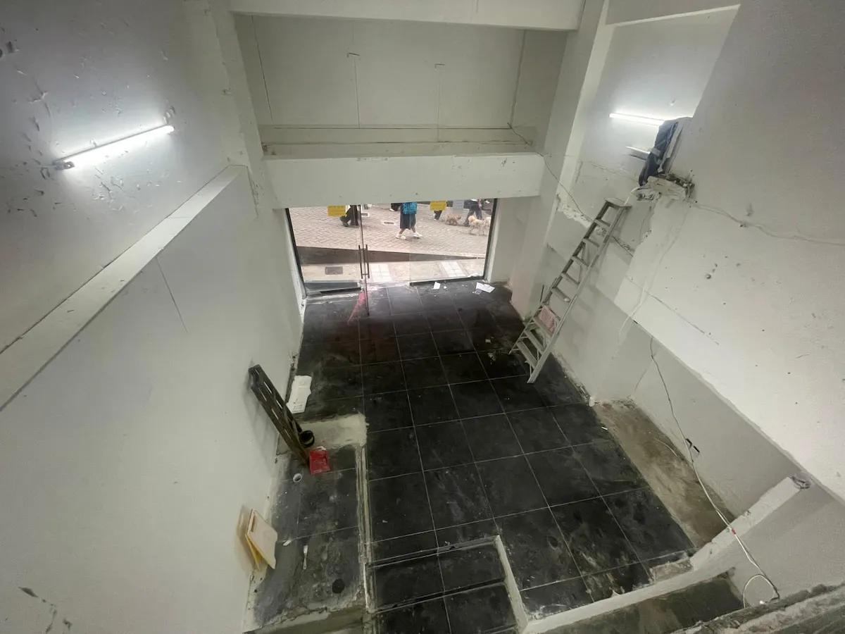 Ref#3623: Spacious, partially renovated room with white walls, black floor tiles, ladder, and some construction materialsideal for rent as a restaurant or shop. Direct entrance from the street.