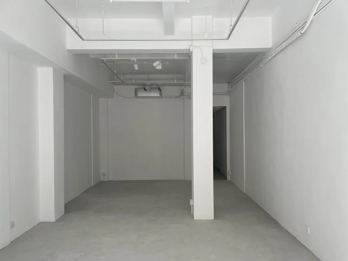 Ref#3624 features a minimal white room with concrete floors, high ceiling, exposed pipes, a central pillar, and an open doorwayideal for office rental. The clean, well-lit space offers flexibility for various business needs.