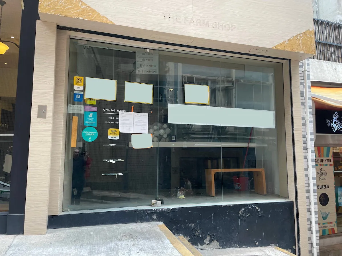 Storefront Ref#3638 features large glass windows obscured by opaque signs, hinting at potential rental. A wooden bench is seen inside, the street slopes upward to the left, and the shop name is faintly visible above the window.