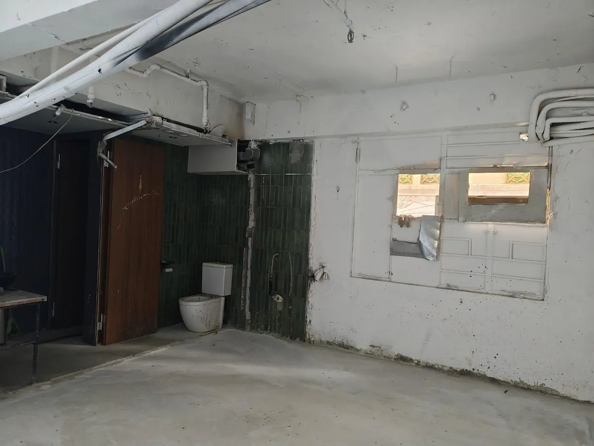 Ref#3646 features an unfinished room with white walls, exposed pipes, a toilet in one corner, two small windows, and a concrete flooran adaptable space ideal for a creative restaurant or unique shop rental.