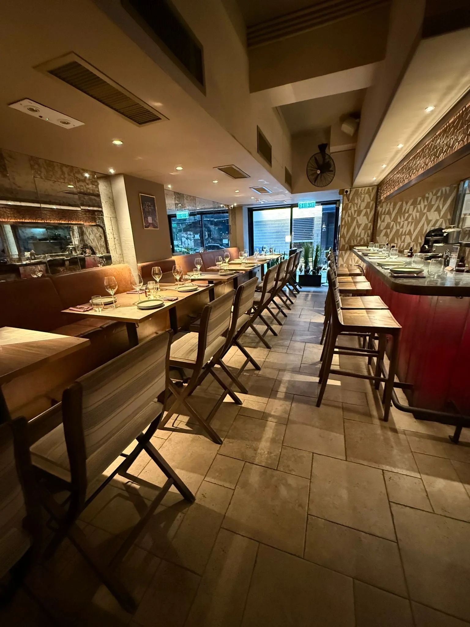 Ref#3654 features a warmly lit restaurant with wooden tables, chairs, set place settings, and a bar with stools an inviting, stylish space ideal for anyone looking to rent a welcoming restaurant venue.