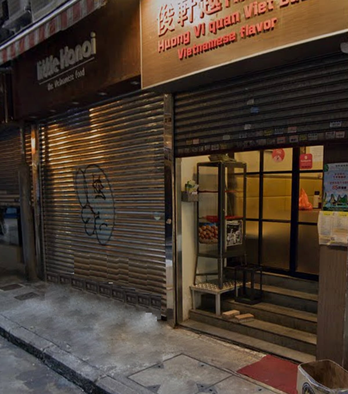 Ref#3669: A Vietnamese restaurant with a partially open metal shutter, "Huong Vi quan Viet Sea" signage, glass door entrance, and menu stand—ideal for renting as shop or restaurant space.