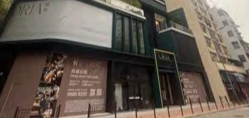 Ref#3665 is a modern black and white commercial building with large windows and ORIA signage, ideal for shop or office rental, located on a city street with brick pavement and metal posts.