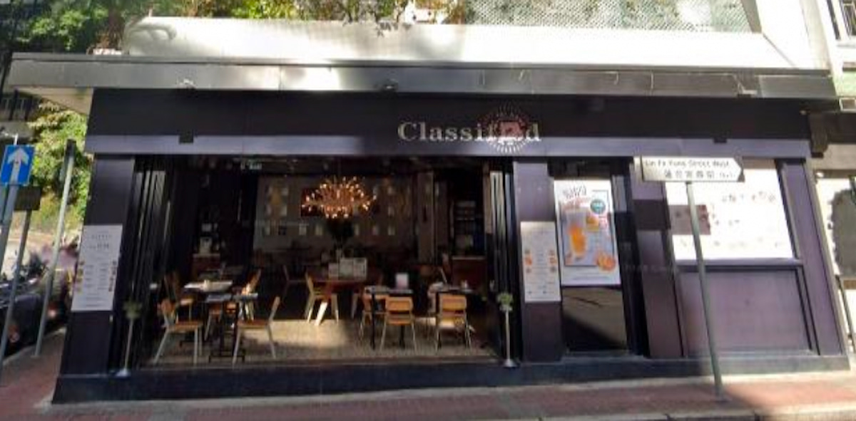 Street view of a vibrant area featuring Ref#3659—a cafe with open windows, wooden tables and chairs, and menu boards outside—perfect inspiration if you're interested in renting restaurant or shop space.